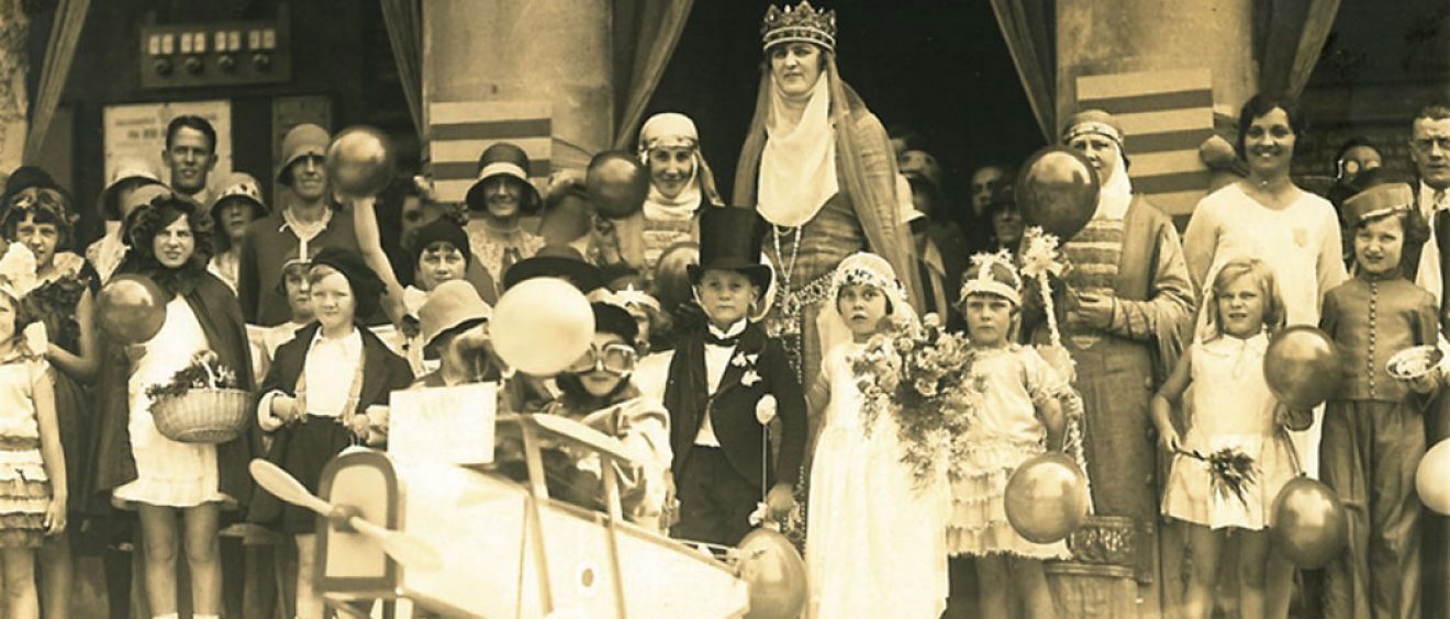 children and adults dressed up in costumes holding balloons