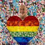 photo of Damien Hirst holding rainbow heart shape with butterfly shapes