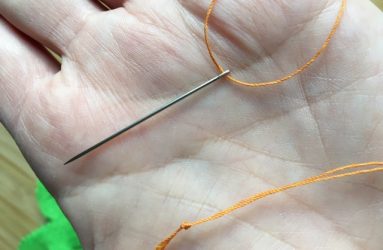 threaded needle with knotted end of thread
