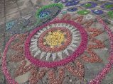 Diwali Rangoli incorporated into peacock design using pink, red, yellow and white gravel in circle design