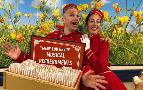 Performers dressed in red as ushers with tray of 'musical refreshments'