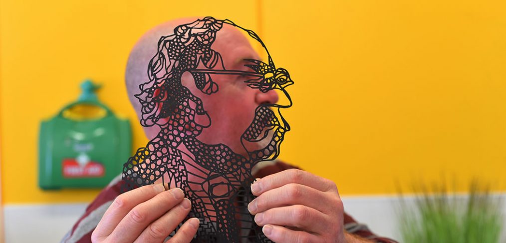 Man holds up outline black and transparent image of himself alongside his own side profile