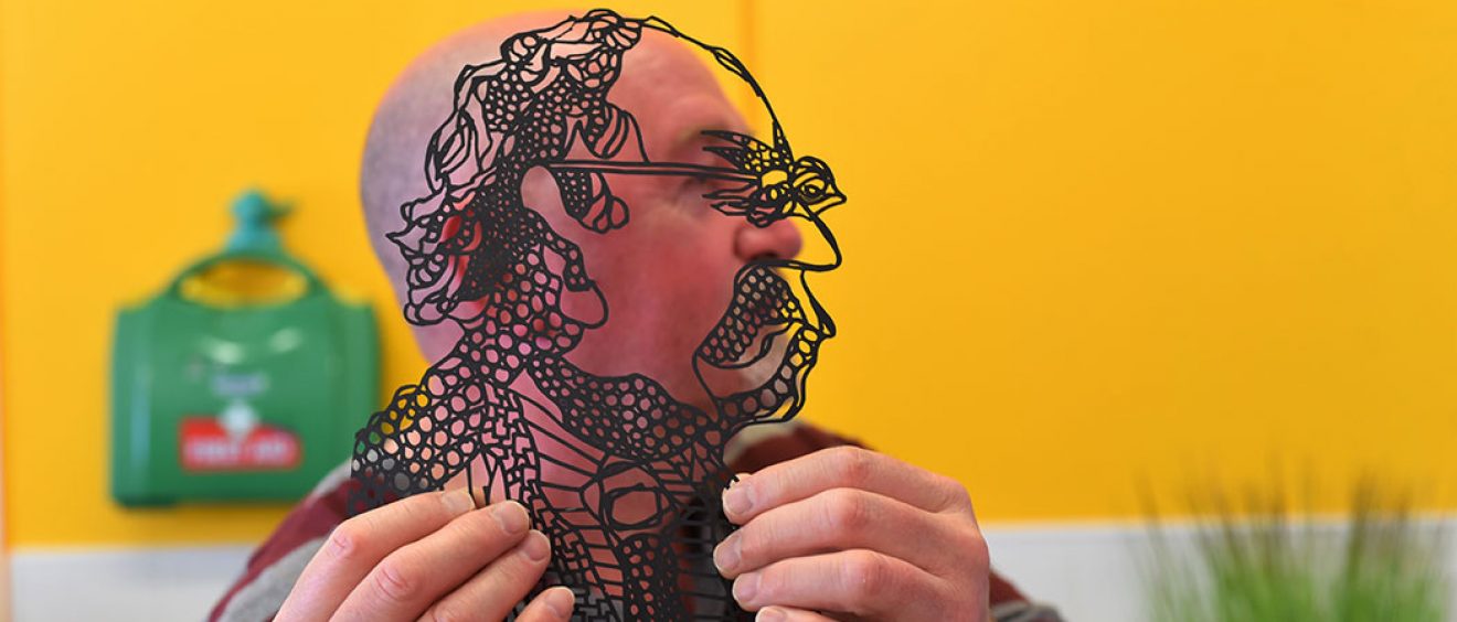 Man holds up outline black and transparent image of himself alongside his own side profile