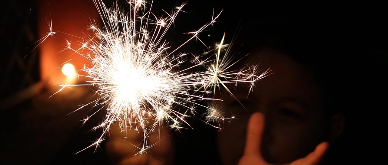 hands holding a sparkler in the dark