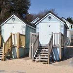 photograph of pastel coloured beach huts with wooden steps leading up to doors