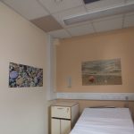 Beach themed artworks and coloured ceiling tiles above bed