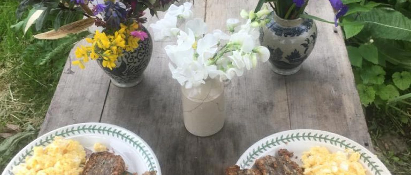 scrambled eggs and bread on plates on outside table set with flowers in vases