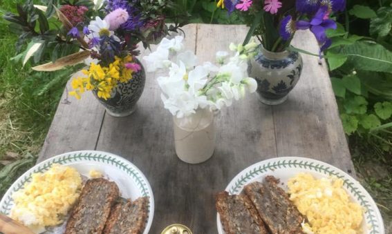 scrambled eggs and bread on plates on outside table set with flowers in vases