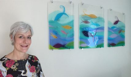 Sue King with her tryptich of fused glass panels showing fish amongst waves