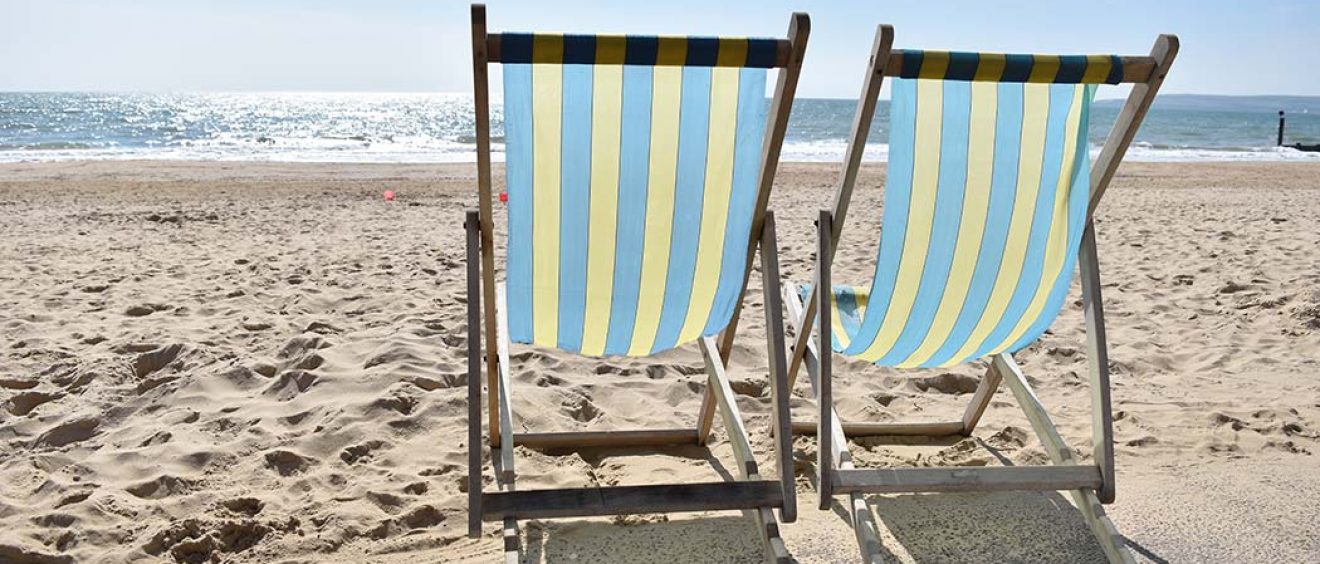 photograph of two blue and yellow deckchairs on the beach