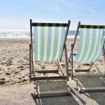 photograph of two blue and yellow deckchairs on the beach