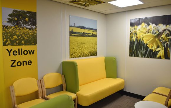 Yellow coloured seating with yellow wall panel. rape seed field artwork and daffodil artwork