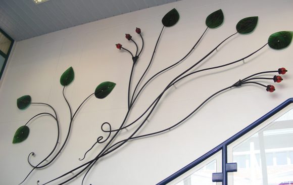 metal and glass sculpture of leaves and seed pods winding up staircase wall