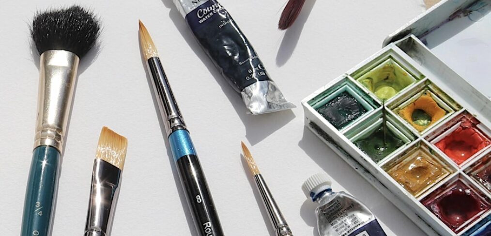 Watercolour brushes alongside paint box