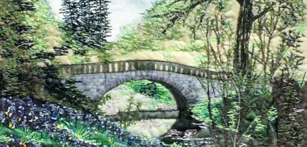 stone arch bridge over stream, yellow and blue wild flowers on bank, trees surround using fabric and machine embroidery