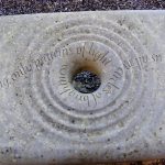 Close up of stone bench with hold and ripple effect carved stone with poetry