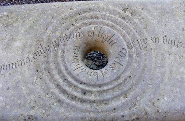 Close up of stone bench with hold and ripple effect carved stone with poetry