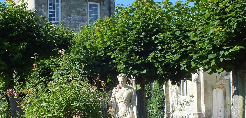 statue in gardens with lavender in front of house